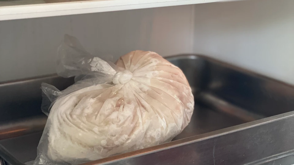 en frosen madvare i pose bliver tøet op i køleskabet