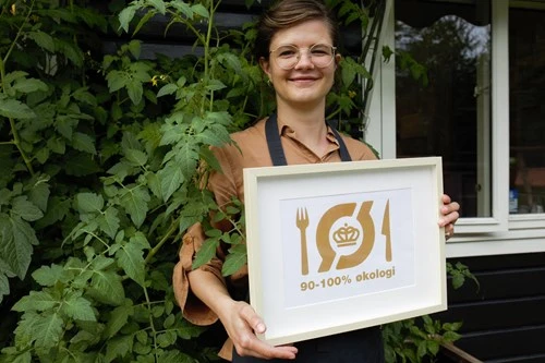 billede af dame holdende Det Økologiske Spisemærke i guld 