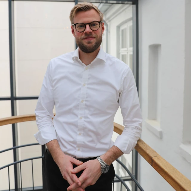 Mand i hvis skjorte står på en trappeafsats