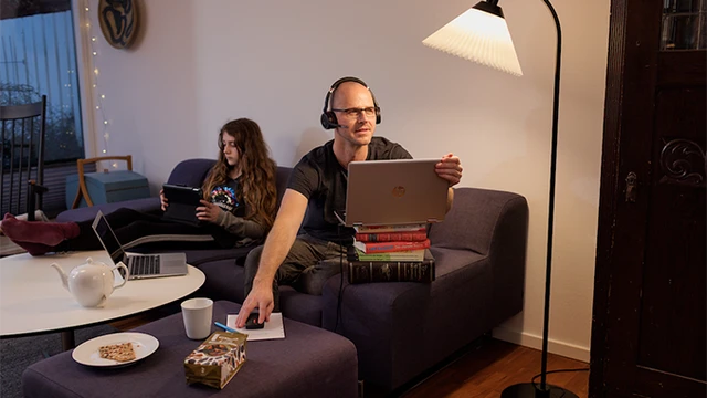 Bannerbillede: mand i sofa, der arbejder hjemmefra med datteren i sofaen