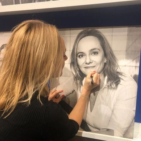 Kvinde skriver med kuglepen på foto af sig selv.