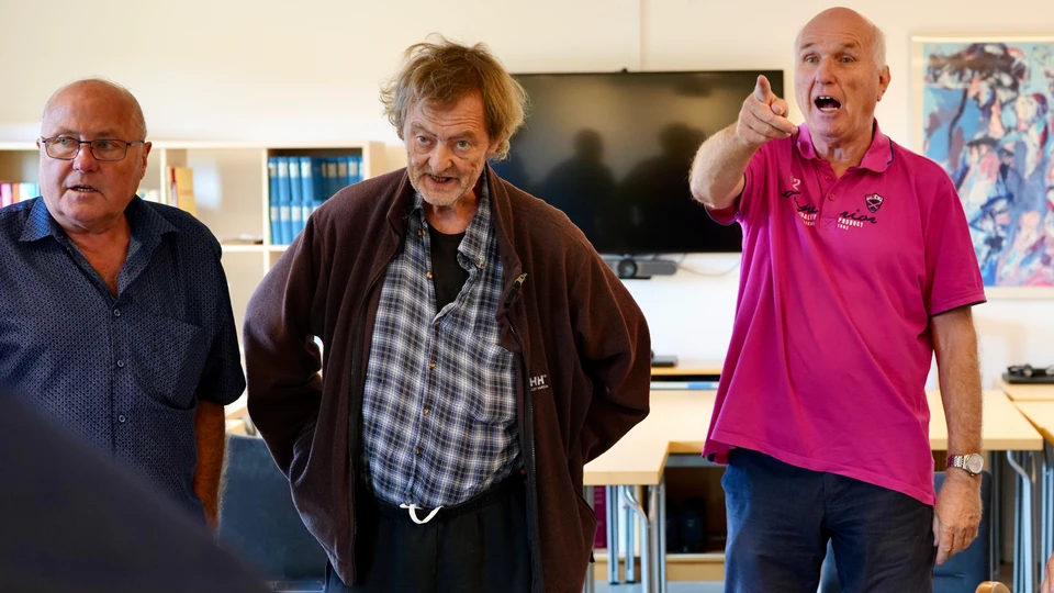 Tre deltagere fra demenskoret står og synger