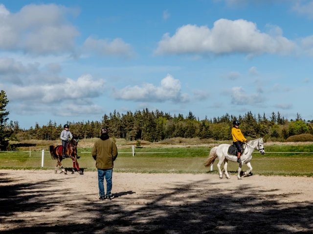 To ryttere, der undervises på udendørs ridebane