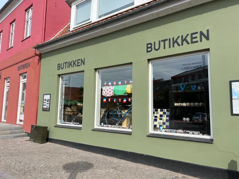 En butiksfacade ud imod en bygade. Den hedder "Butikken", og er en del af "Vordingborg Sociale Virksomhed".