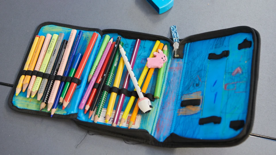 Åbent penalhus med blyanter på et bord