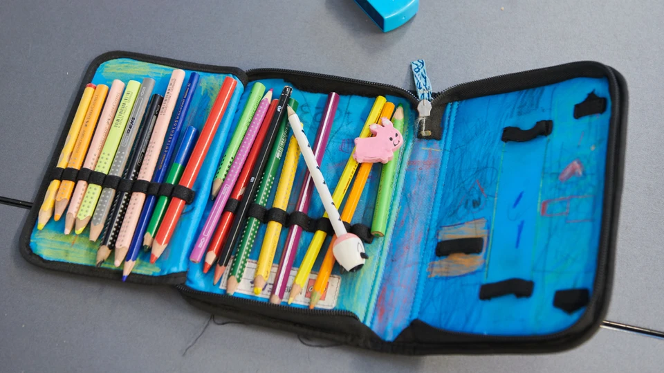 Åbent penalhus med blyanter på et bord