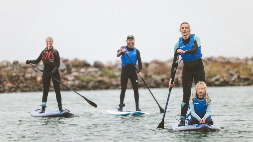 Børn og voksne på paddleboard i Klintholm Havn