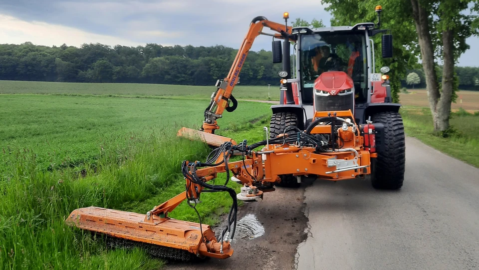 Billede af en rød traktor med en græsklipper monteret foran