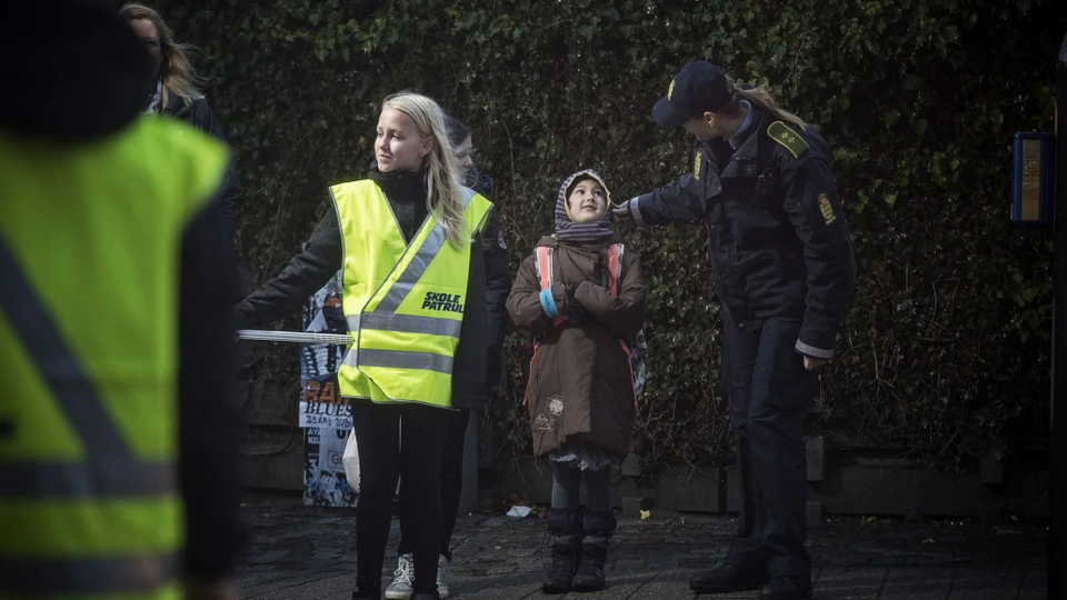 Billede af skolepatrulje, der sammen med en kvindelig politibetjent hjælper børn over vejen