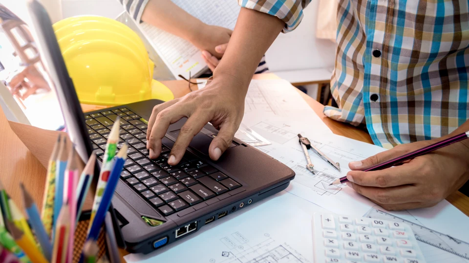 Billede af mand, der kigger på byggetekniske tegninger ved en bærbar computer