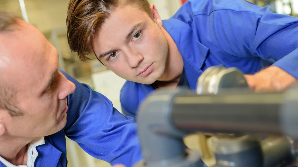 Ung mand kigger på rør med voksen medarbejder