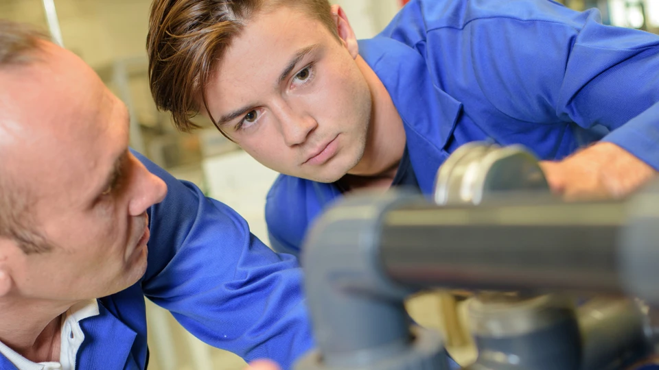 Ung mand kigger på rør med voksen medarbejder