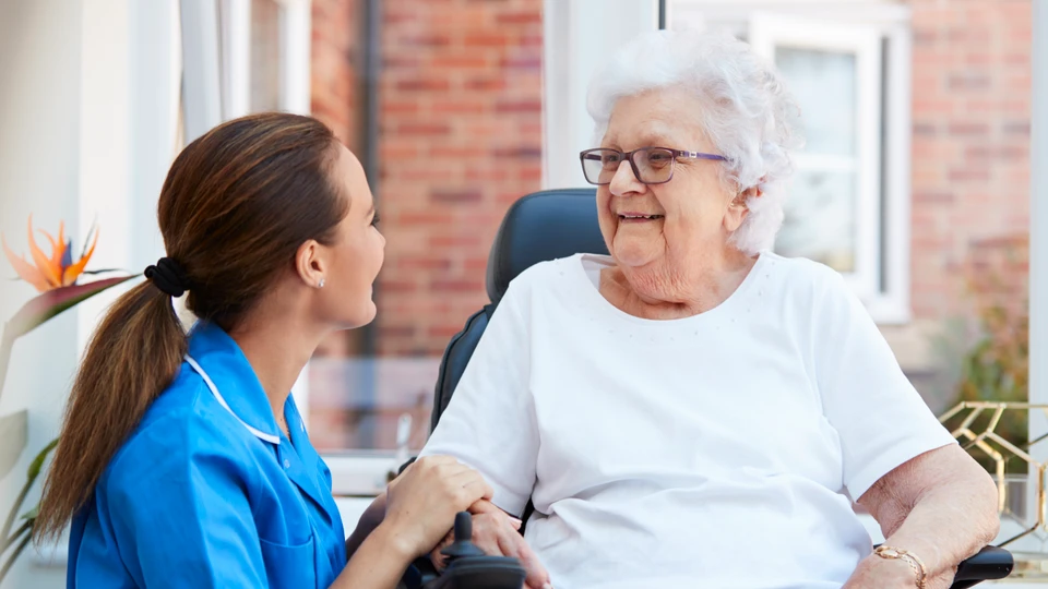 Plejer taler med ældre kvinde i rullestol