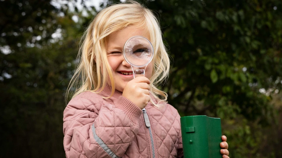 Billede af en børnehave-pige med et forstørrelsesglas