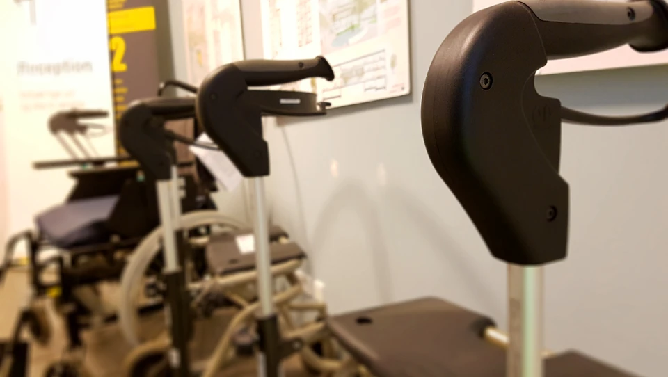 Billede af en række rollatorer og kørestole i en offentlig lignende bygning