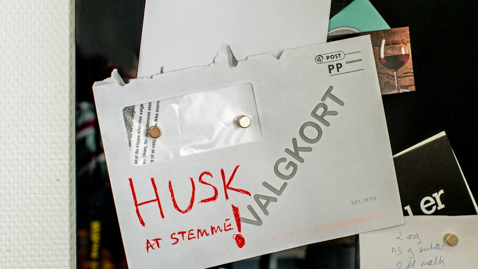 Billede af en kuvert med et valgkort, der hænger på en opslagstavle