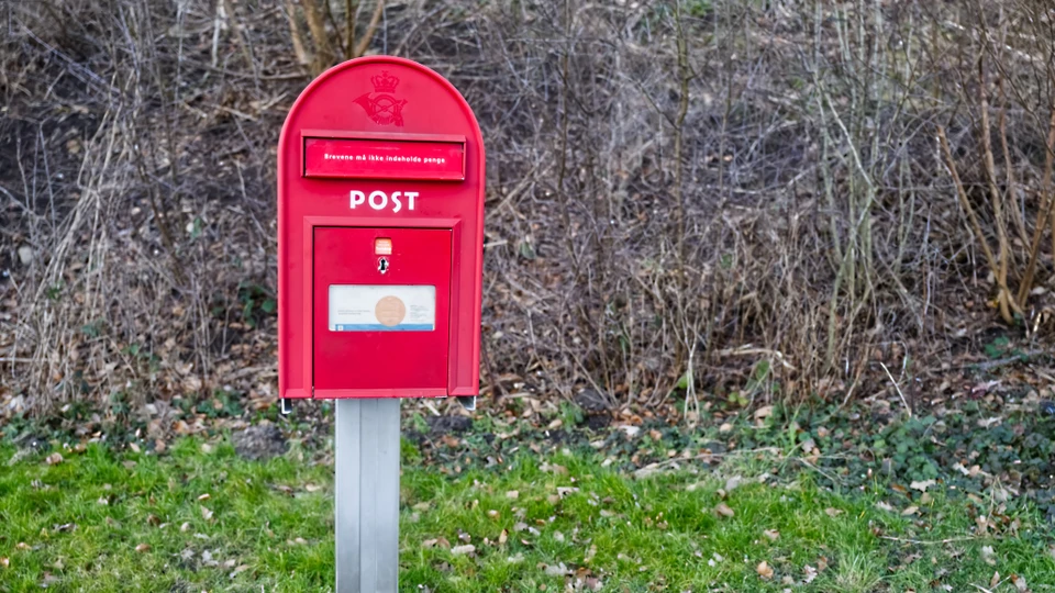 Billede af en rød postkasse, der står frit i en vejkant