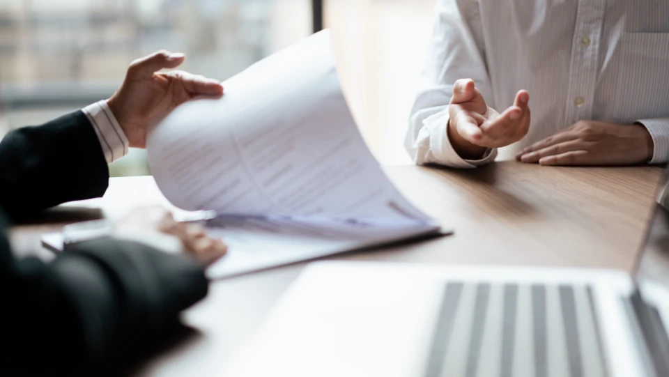 Billede af to mennesker, der sidder ved et bord og kigger i papirer 